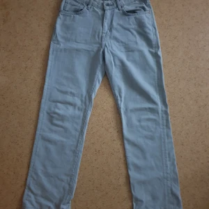 Ljusgrå straight jeans från Never Denim - Säljer ett par ljusgrå jeans från Never Denim med straight passform och klassisk femficksdesign. Byxorna har lågmidja och stängs med knapp och dragkedja. Perfekta till en avslappnad stil.