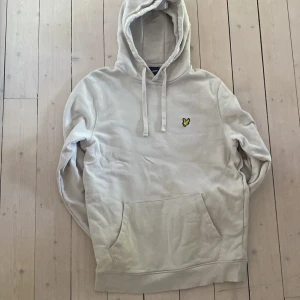 Beige hoodie från Lyle & Scott - Säljer en beige hoodie från Lyle & Scott med klassisk gul logga på bröstet. Tröjan är i storlek M och i mycket bra skick. Inte använd särskilt mycket. Endast 199kr, Säljer på grund av att den blivit för liten. Tröjan har huva med dragsko och en stor magficka framtill. Perfekt för en avslappnad och uppklädd stil.