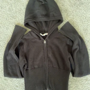 Svart croppad hoodie med dragkedja från Gina tricot - Säljer en svart croppad hoodie med dragkedja framtill och huva. Tröjan har långa ärmar och ribbad nederkant som ger en snygg passform. Perfekt för en avslappnad och trendig look. Väldigt stretchig så passar större storlekar. Har inte använt någon gång. Läs bio innan köp💕💕