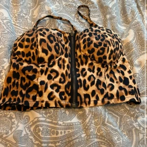 Leopardmönstrad korsettopp med dragkedja - Säljer en snygg leopardmönstrad korsettopp med smala axelband och dragkedja framtill. Toppen har vadderade kupor och är storlek S! 