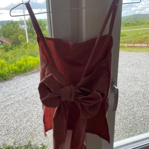 Rosa  linnetopp med stor rosett och öppen rygg - Supersöt rosa linnetopp med smala axelband och en stor rosett i ryggen. Toppen är croppad och har en slät, enkel framsida. Perfekt för varma dagar när du vill sticka ut lite extra. Passar många storlekar då det knyts i ryggen. Jag har sytt den sjölv. 