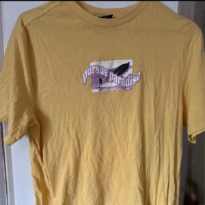 Gul T-shirt  - En gul snygg t-shirt med texten ”pursue paradise” använd några gånger!💕
