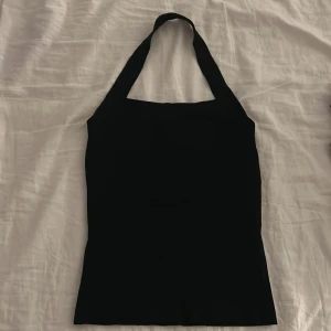 Svart halterneck linnetopp från H&M - Säljer en svart halterneck linnetopp från H&M. Toppen har en enkel och stilren design med breda axelband som går runt nacken. Toppen har en öppen rygg. Perfekt att matcha med jeans eller kjol för en trendig look.