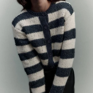 Randig kofta från ZARA - Supermysig kofta från ZARA med breda svarta och vita ränder. Koftan har lång ärm, rund halsringning och knäppning framtill med fem knappar. Stickad i ett fluffigt material som känns både trendigt och bekvämt.