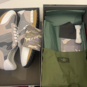 Valentino Rockrunner sneakers i grått och beige - Säljer ett par Valentino Rockrunner sneakers i grått, beige och vitt med kamouflagemönster. Skorna har vita snören, gummisula med nitar på hälen och detaljer i mocka och mesh. Kommer med originalkartong, extra skosnören och dustbag.