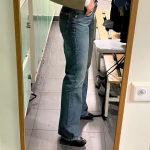 Blå bootcut jeans - Säljer ett par klassiska blå bootcut jeans med normal passform och hög midja. Jeansen har en tidlös look med fyra fickor och dragkedja. Perfekta till sneakers eller boots för en snygg vardagsstil.
