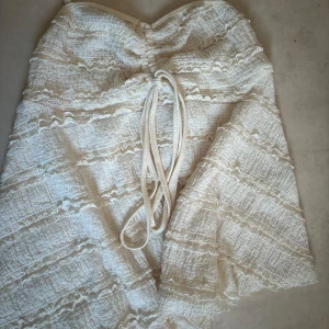 Vit topp med knyt och volang - Supersöt vit topp med tunna axelband och omlottknytning framtill. Klänningen har volangdetaljer och struktur i tyget som ger en romantisk känsla. Perfekt för sommarens alla tillfällen. Pris kan diskuteras och skriv för fler bilder (oanvänd)💓