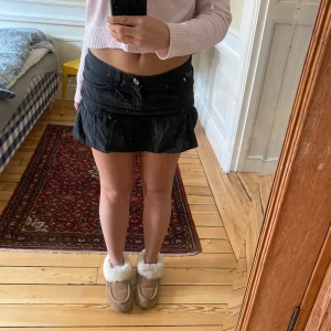 Svart minikjol från Peak Performance - Svart minikjol från Peak Performance med volang nertill och broderad logga på ena fickan💗