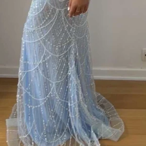 Ljusblå långklänning med pärldetaljer - Säljer en magisk ljusblå långklänning med glittriga pärldetaljer och offshoulder-design. Klänningen har en elegant passform och är perfekt för bal eller fest. Materialet är skimrande och ger en lyxig känsla. Pris kan diskuteras!