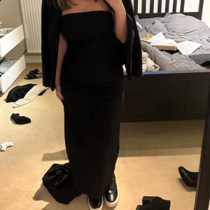 Svart axelbandslös klänning från Zara - Snygg svart axelbandslös klänning från Zara med en elegant slits bak. Perfekt för en stilren look. Klänningen har en tight passform som framhäver figuren. Använd vid ett tillfälle ❤️ klänning är som ny