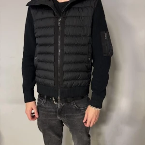 Moncler Cardigan Jacka - Säljer denna jacka från Moncler med stickade ärmar och quiltad front. Jackan har dragkedja framtill, fickor med dragkedja och en liten ficka på ärmen. Perfekt för kyliga dagar. Skriv till mig om ni har mer funderingar eller vill ha mer bilder! Storlek S men passar M! Obs kan även gå ner i pris vid snabb affär