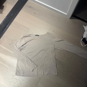 Beige långärmad topp från Zara - Säljer en enkel och stilren beige långärmad topp från Zara. Tröjan har rund halsringning och är tillverkad i mjukt bomullsmaterial. Perfekt att matcha med jeans eller kjol för en clean look.