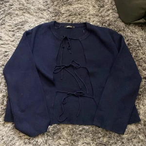 Mörkblå tröja med snörning från Gina Tricot - Mörkblå långärmad tröja från Gina Tricot med snygga snörningsdetaljer framtill. Tröjan har rund halsringning och är tillverkad i ett mjukt material som känns skönt mot huden. 