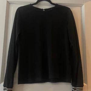 Svart glittrig långärmad topp från Petit by Sofie Schnoor - Säljer en svart långärmad topp från Petit by Sofie Schnoor med glittrigt material. Enkel och stilren design med rund halsringning och liten knapp i nacken. Perfekt för dig som vill ha något lite extra till outfiten. I bra skick💕
