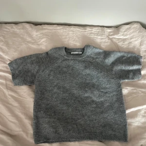 Grå stickad kortärmad tröja - Mysig grå stickad tröja från 157 med korta ärmar och rund halsringning. Perfekt för lager-på-lager och enkel att matcha med olika outfits. Mjuk och skön känsla tack vare det stickade materialet. Storlek är 160 men sitter XS/S🥰! Använd fåtal gånger och i mycket bra skick. 