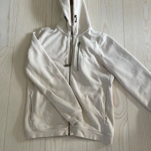 Beige hoodie från Sail Racing - Säljer en fet varm hoddie från sälj racing. Stl 170, använt några gånger men inga skador, hör av er vid frågor