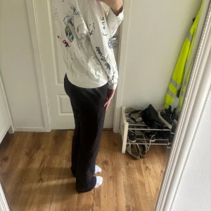 Vit hoodie med tryck från Zadig & Voltaire - Vit hoodie med dragkedja och huva från Zadig & Voltaire. Jackan har tryck och text i svart och rött samt flera små illustrationer över hela plagget. Fickor framtill och ribbade muddar vid ärmslut och nederkant.