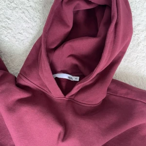 Vinröd hoddie från lager 157 - Säljer en vinröd hoddie med luva och magficka framtill. Aldrig använd så den är i jätte bra skick köpt för 200kr