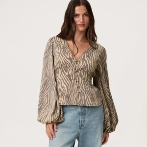 Zebramönstrad blus från Adoore strl 42 - Supersnygg blus från Adoore med zebramönster i beige och brunt. Blusen har v-ringning, knappar framtill och vida, långa ärmar . Endast använd en gång, tyvärr för stor för mig.🥰💕