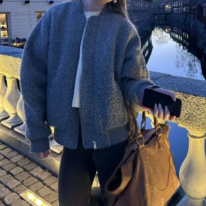 Grå teddyjacka med dragkedja - Säljer en oversized grå teddyjacka med dragkedja framtill och ribbade muddar. Jackan har en mysig, fluffig textur och är perfekt för kyliga dagar. Enkel och stilren design som passar till det mesta. Snygg att slänga över en hoodie eller t-shirt. Storlek L men sitter som en S