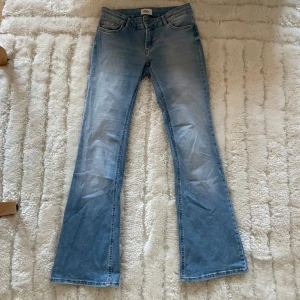 Ljusblå bootcut jeans från ONLY - Säljer ett par ljusblå lågmidjade bootcut jeans från ONLY i klassisk denim. Jeansen har fem fickor, normal passform och snyggt utsvängda ben. Perfekta för dig som vill ha en avslappnad men trendig look.