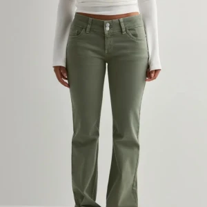 Olivgröna bootcut byxor - Snygga olivgröna bootcut byxor med klassisk femficksdesign och dekorativa sömmar på bakfickorna. Byxorna har normal passform och stängs med dubbla knappar framtill. Perfekta för dig som vill ha en stilren och trendig look.