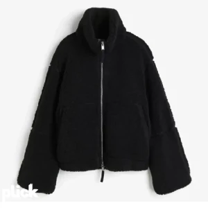 Svart teddyjacka med dragkedja - Mysig svart teddyjacka med hög krage och grov dragkedja framtill. Jackan har två stora fickor och en oversized passform som ger en chill vibe. Perfekt för kalla dagar när du vill vara både varm och snygg.