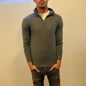 Grå half zip tröja från Manoukian - Snygg grå långärmad tröja från Manoukian med half zip och hög krage. Tröjan är stickad och har en clean, slim passform som sitter riktigt bra. Perfekt för dig som gillar stilrena plagg med lite edge. Passar till jeans eller chinos för en chill look. 100% Acryllique  Nypris 899Kr. Mitt pris:199Kr ✅