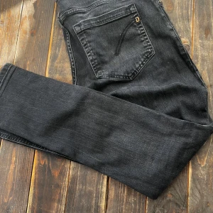 Svarta Dondup jeans - Snygga svarta jeans från Dondup med knäppning framtill och klassiska fem fickor. Modellen är George och Jeansen har en lätt tvättad look och raka ben.