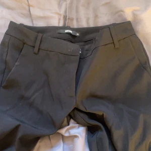 Svarta lågmidjade kostymbyxor från Bik Bok - Svarta kostymbyxor från Bik Bok i klassisk rak modell med hällor för bälte och diskreta fickor.modell Vera. Byxorna har en stilren look och är tillverkade i ett mjukt tyg som känns bekvämt hela dagen. Perfekta för en clean och snygg outfit. Sytt en egen slit för att dom ska va snyggare vid skorna