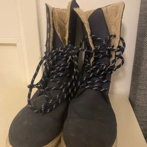 Mörkblå fodrade kängor med snörning - Snygga mörkblå kängor med grov sula och vit kontrastsöm. Fodrade med mjukt beige foder för extra värme. Klassisk snörning med svarta och vita skosnören. Perfekta för kalla dagar och en cool streetstil.