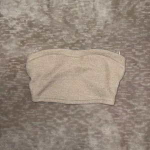Beige bandeau tubtopp - Snygg beige bandeau tubtopp i mjukt stickat material.  Den är väldigt kort och stretchig. Toppen har använts en gång. 