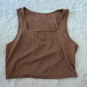 Brun randig linnetopp från SHEIN - Säljer en brun, randig linnetopp från SHEIN i storlek XL. Toppen har en fyrkantig ringning och är ärmlös, perfekt för varma dagar. Materialet är mjukt och stretchigt, vilket gör den riktigt bekväm att bära.