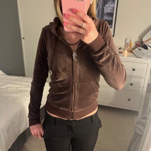 Brun velour hoodie Juicy Couture! - Säljer en brun hoodie från Juicy Couture i mjuk velour med glittrande strassdetaljer😚. Tröjan har huva, snörning, dragkedja och fickor framtill. På ryggen står det 'Juicy' i stora strasstenar och på bröstet finns ett litet JC-emblem. Har inte hittat några defekter och säljer eftersom att den inte längre kommer till användning. Har använts lite så väldigt bra skick och priset kan diskuteras!🤗