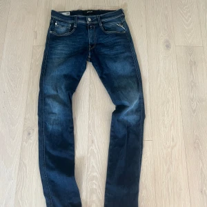 Replay Anbass mörkblå jeans - Snygga mörkblå Replay Anbass jeans med klassisk femficksdesign och kontrastsömmar. Modellen har rak passform och normal midja. Materialet är mjukt jeans med lite stretch för extra komfort. Bakfickan har Replay-logga. Storlek 31