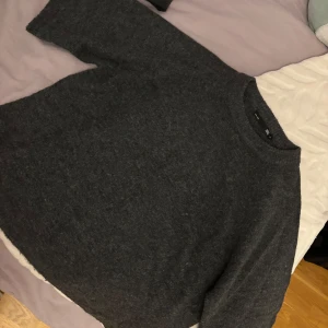 Mörkgrå stickad tröja  - Mysig mörkgrå stickad tröja från med rund halsringning och avslappnad passform.Tröjan har korta ärmar.