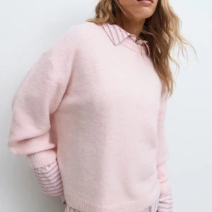 Ljusrosa stickad tröja oversized - Supermysig ljusrosa stickad tröja med loose passform och långa ärmar. Tröjan har ribbade muddar vid ärmslut och nederkant, vilket ger en chill och avslappnad vibe. Perfekt att styla över en skjorta eller till jeans för en soft look.