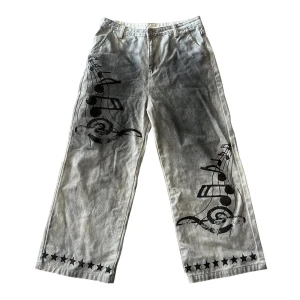 Mud washed white jeans  - Unika grå byxor med bred passform och coolt svart musiknot-tryck på framsidan. Nedtill och baktill finns svarta och röda stjärnor som ger extra edge. Byxorna har hällor för bälte och stora bakfickor. Perfekta för dig som vill sticka ut. Helt nya, Storlek L - W33ish, 32~34. skriv för frågor info! ifrån japan 