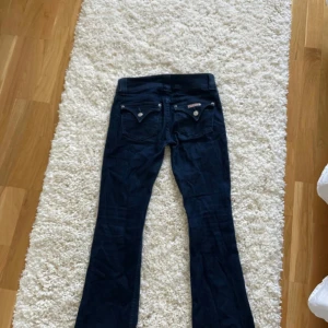 Mörkblå bootcut jeans  - Snygga mörkblå jeans från Replay med bootcut passform. Klassiska femficksdetaljer, dubbla knappar i midjan och coola bakfickor med knapp. Köpta second hand och den tidigare ägaren sprättade upp jeansen längst ned så dem skulle bli lite längre, det är snyggt gjort och det visas på sista bilden
