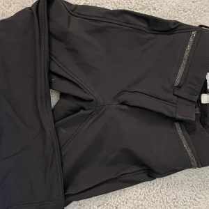 Svarta ridbyxor från CRW med silikonprint - Svarta ridbyxor från CRW med silikonprint på insidan av benen för extra grepp. Byxorna har dragkedja fram och bälteshällor i midjan. Snygg och sportig design, perfekta för ridning.