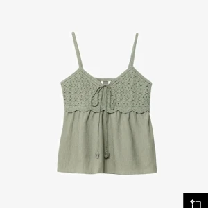 Grön linnetopp med virkade detaljer - Söt ljusgrön linnetopp med virkade detaljer upptill och smala axelband. Toppen har knyt framtill och en lätt vågig kant vid bysten. Perfekt för varma dagar och enkel att matcha med jeans eller kjol.