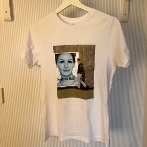 Vit t-shirt med Notting Hill tryck - Vit t-shirt från Uneek i bomull med tryck från filmen Notting Hill på framsidan. Klassisk passform med rund hals och korta ärmar. Perfekt för dig som gillar film och vill ha en unik t-shirt i garderoben. Köpt i london men passade tyvärr inte så helt oanvänd.Bara att höra av dig!