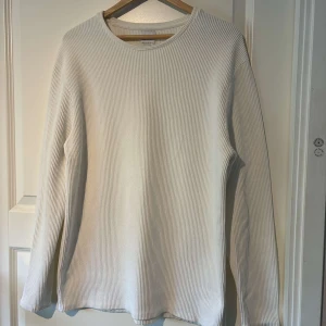 Vit ribbad långärmad tröja från Zara - Säljer en stilren vit långärmad tröja från Zara. Tröjan är ribbad och passar L. Använd någon enstaka gång.