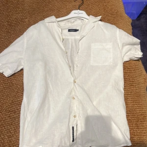 Vit linneskjorta  - Säljer en stilren vit skjorta i linne . Skjortan har korta ärmar, klassisk krage, bröstficka och knäppning framtill. Perfekt för varma dagar och enkel att matcha med jeans eller shorts. Nypris 700 kr