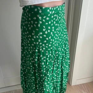 Grön blommig långkjol från H&M - Säljer en grön långkjol från H&M med vita blommor. Perfekt till sommaren!🌸