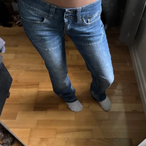 Blå jeansbyxor med raka ben - Säljer ett par klassiska blå jeansbyxor från Veromoda med raka ben och låg midja. Byxorna har slitna detaljer, dubbla knappar i gylfen och fickor med knapp bak. Perfekta för en avslappnad stil. Säljer eftersom de inte kommer till användning. Lite slitage längst ner men inget man tänker på!