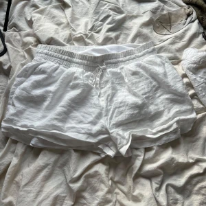 Vita linneshorts med dragsko - Säljer ett par fräscha vita shorts i linne med elastisk midja och dragsko. Storlek 40 ifrån Nelly.
