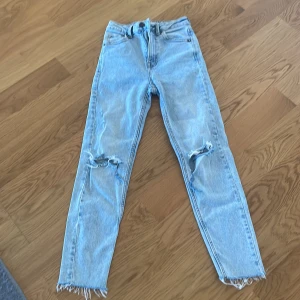 Ljusblå slitna jeans från Stradivarius - Ljusblå jeans från Stradivarius med slim fit och slitningar på båda knäna. Råa kanter nertill och klassisk femficksmodell. Perfekta för en avslappnad och trendig look.