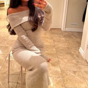 Beige ribbad långklänning med offshoulder - Säljer en superfin beige ribbad långklänning med offshoulder-design. Klänningen har lång ärm och sitter figurnära, perfekt för dig som gillar en stilren och trendig look.