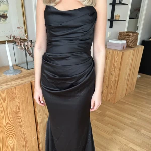 Svart balklänning från ASOS DESIGN - Jättesnygg långklänning från ASOS DESIGN (slutsåld, orginalpris ca 1500kr). Svart bandeau klänning i satin med en figurnära passform. Perfekt till dig som ska gå bal! Skriv för fler biler eller frågor💕